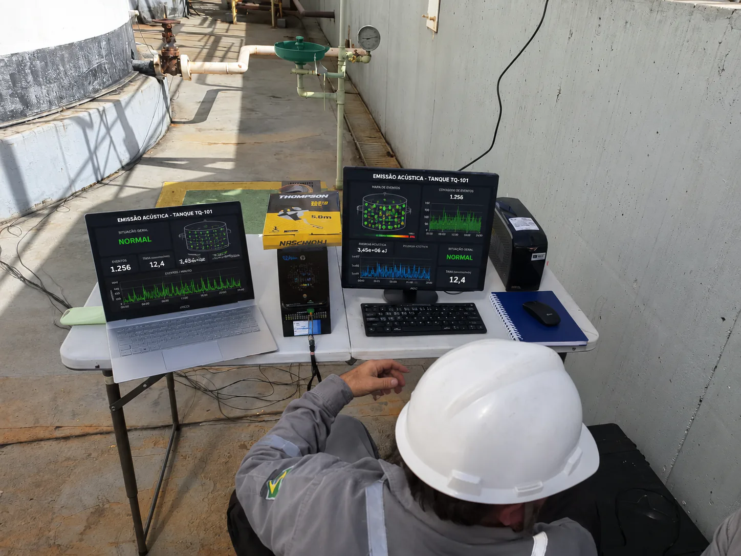 Técnico monitorando ensaio de emissão acústica em um tanque industrial